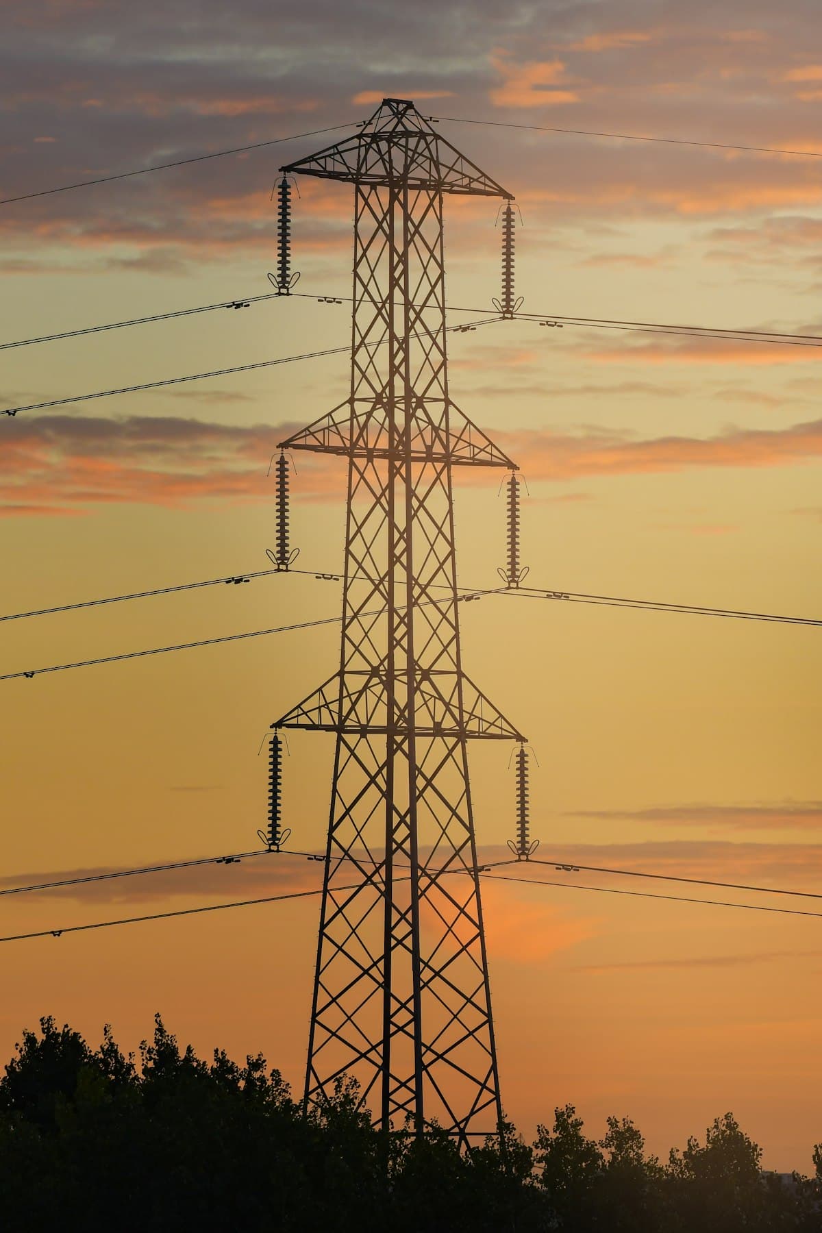 A lattice pylon silhouetted against an amber evening sky